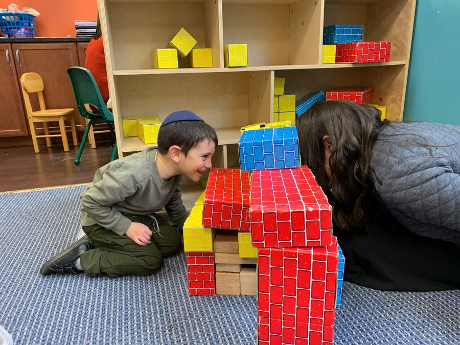 A boy grinning at a therapist through a gap in a block tower