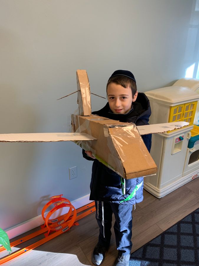 A boy holding a cardboard airplane he built